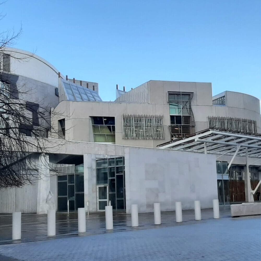Exterior view of a modern building, with geometric shapes and a glass entrance, under a clear blue sky. - Home Instead