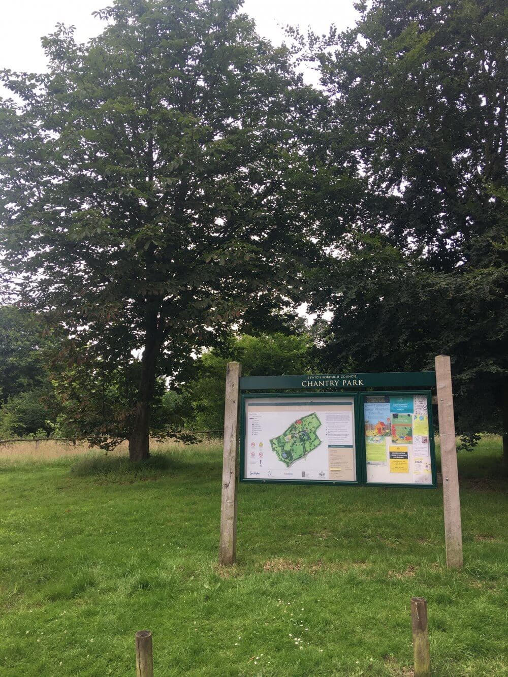 A park information board labeled "Chantry Park" stands amidst green grass and trees. - Home Instead