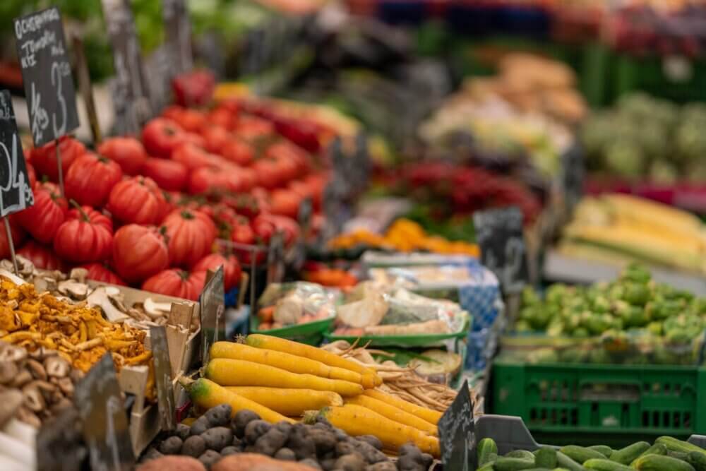 A vibrant assortment of fresh vegetables and fruits on display at a market stall. - Home Instead