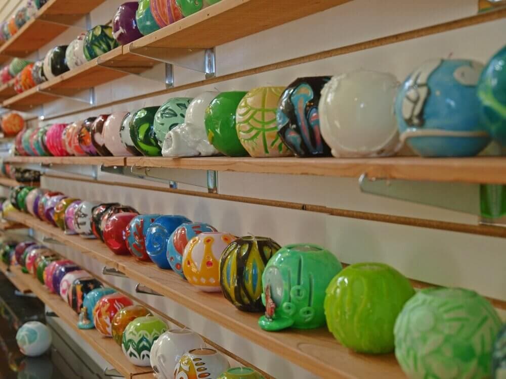 Colorful decorative ceramic spheres on wooden shelves in a store. - Home Instead