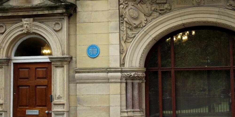 A historic building façade with a plaque reading "Site of Peterloo Massacre 1819" placed between two arched windows. - Home Instead