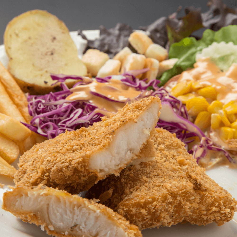 A plate with breaded fish fillets, salad, fries, croutons, and half a baked potato. - Home Instead