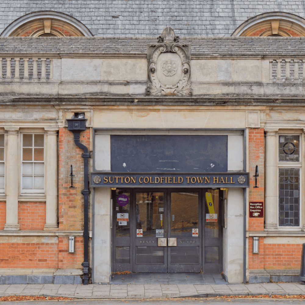 Entrance of Sutton Coldfield Town Hall with a small staircase, signage, and historical architectural details. - Home Instead