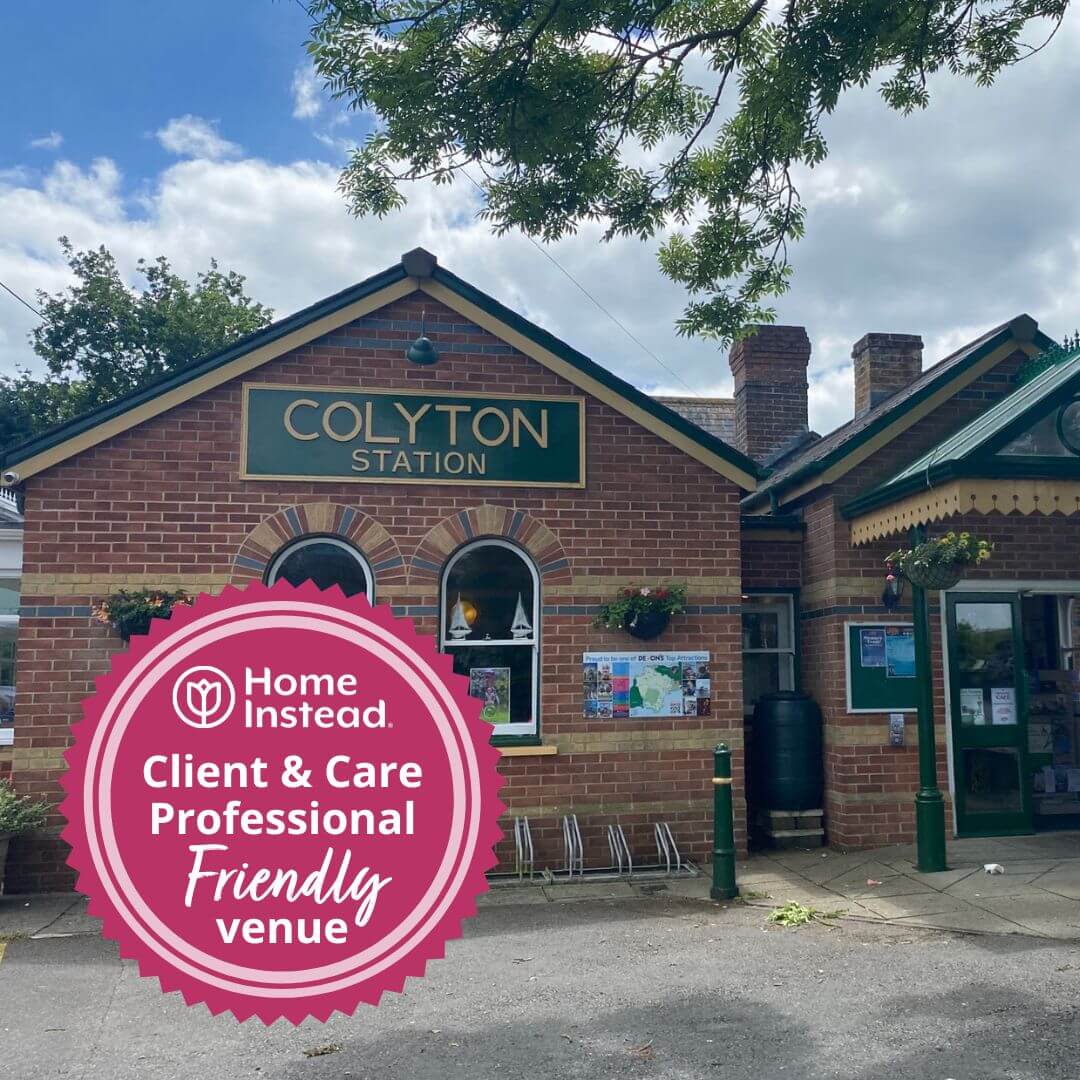 Colyton Station brick building with a Home Instead "Client & Care Professional Friendly venue" badge in the foreground. - Home Instead