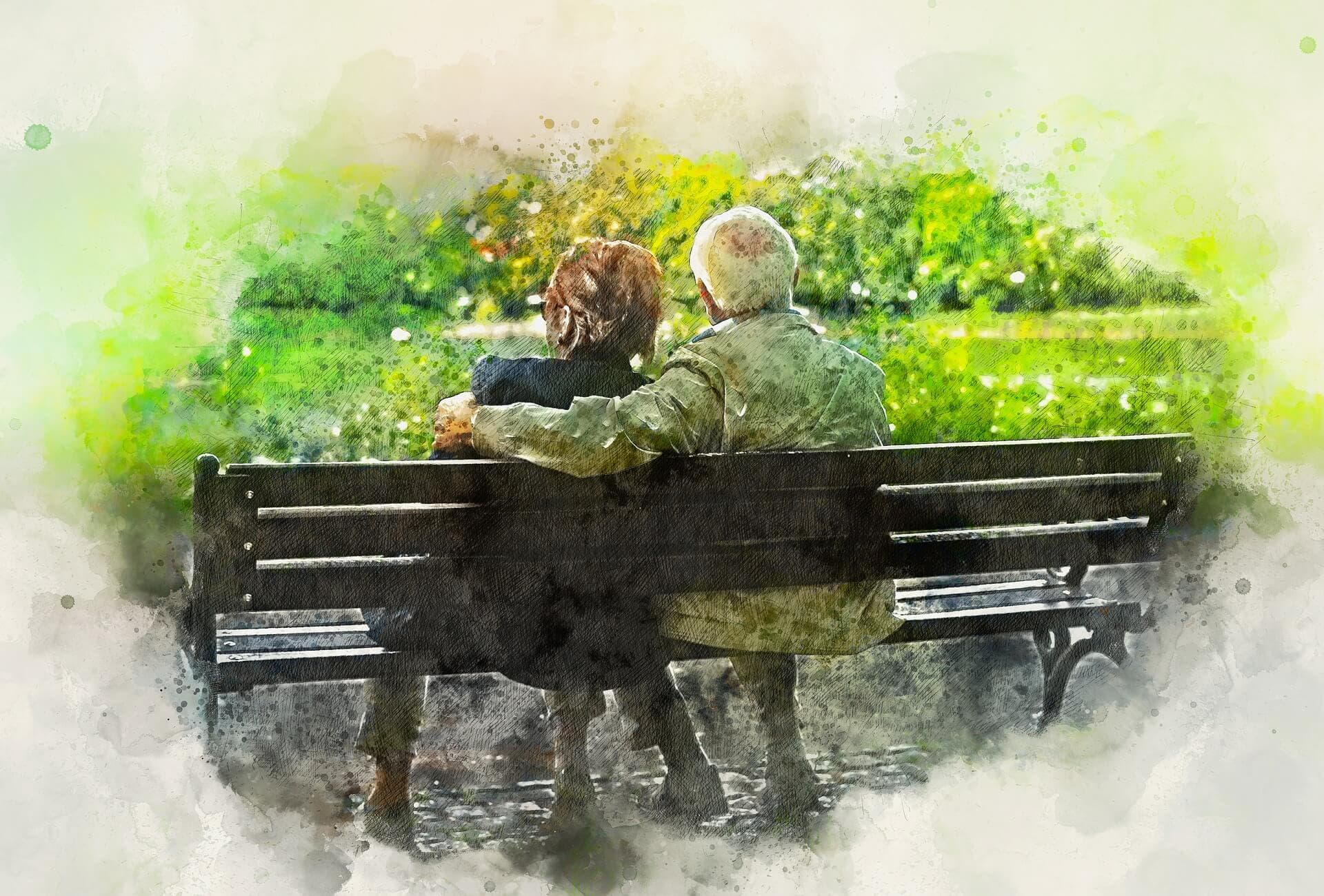 An elderly couple sits closely on a bench in a park, surrounded by greenery and soft light. - Home Instead