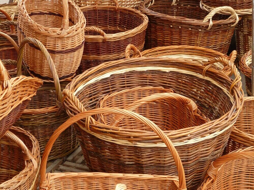 A collection of woven wicker baskets of varying sizes, stacked and arranged closely together. - Home Instead