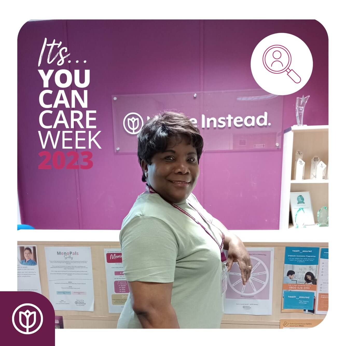A woman stands smiling in front of a purple wall with a sign that reads, “It’s You Can Care Week 2023.”. - Home Instead