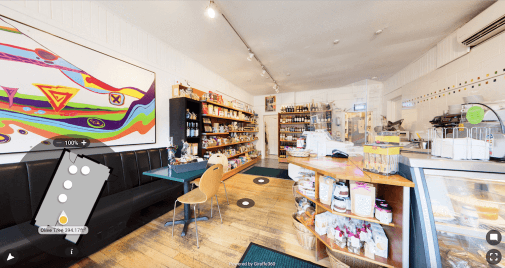 A cozy cafe with shelves of food items, colorful wall art, and seating area with black booths and wooden chairs. - Home Instead