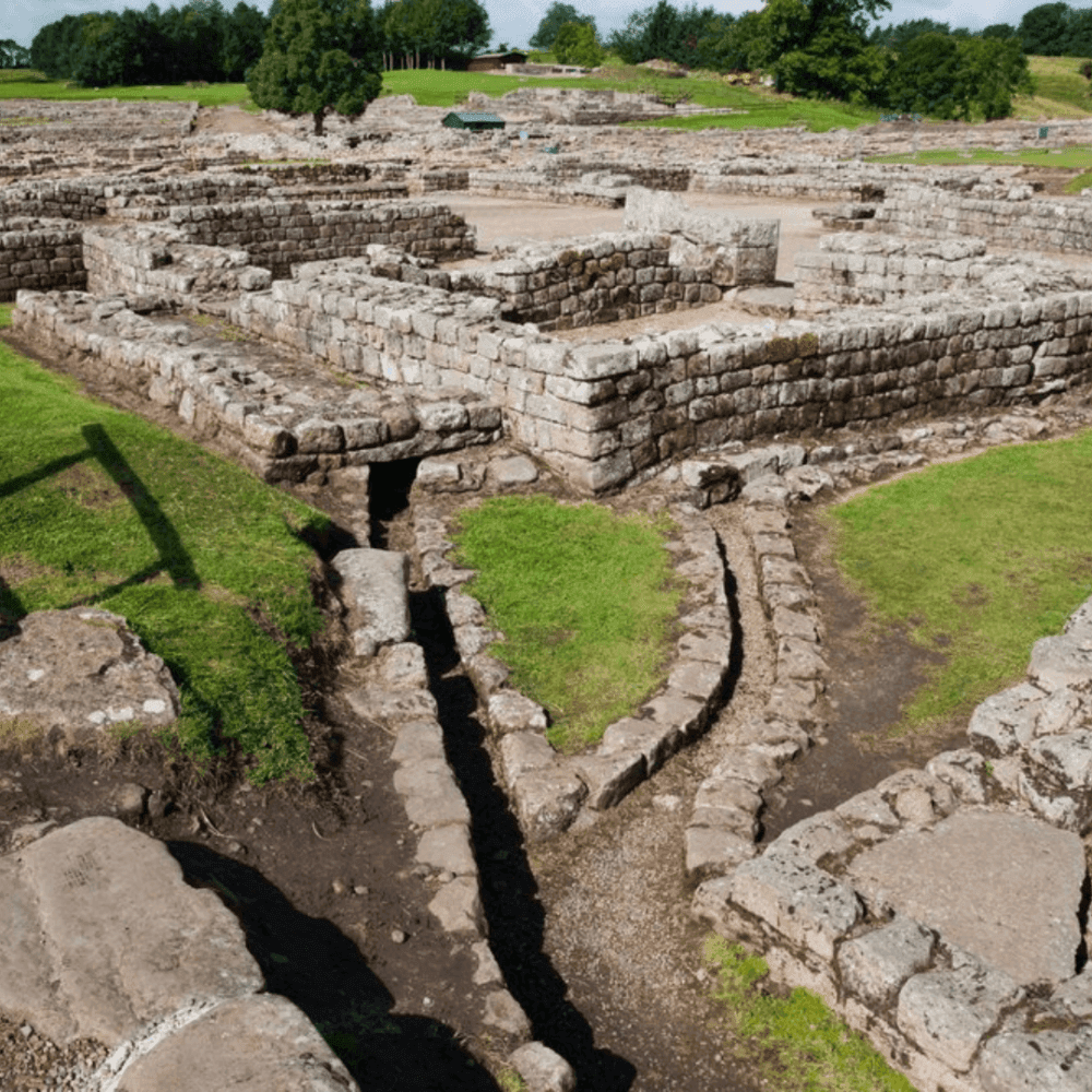Ruins of stone structures and walls with narrow paths among grass, set in a historic archaeological site. - Home Instead