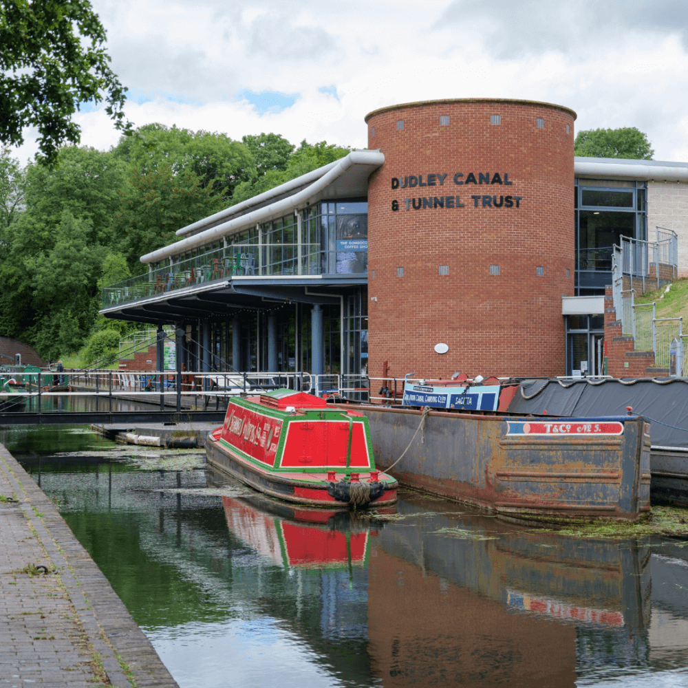 A canal boat is moored at Dudley Canal and Tunnel Trust building on a cloudy day. - Home Instead