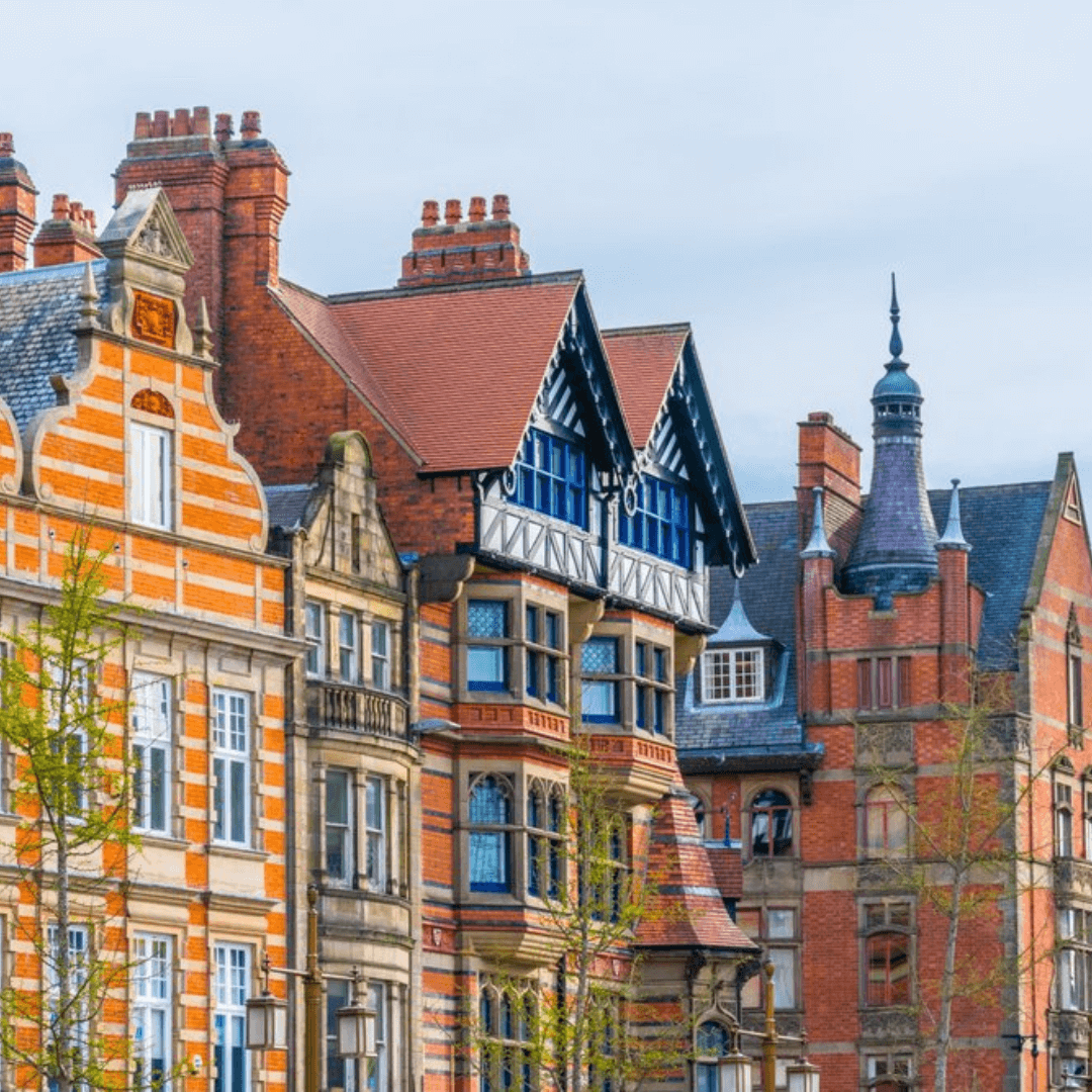 Colorful, historic European buildings with intricate architecture and tall chimneys under a cloudy sky. - Home Instead