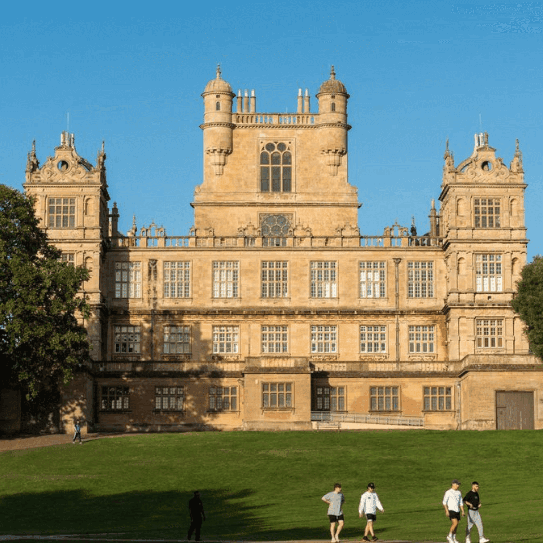 People walking and exercising on a lawn in front of an ornate, historic building under a clear blue sky. - Home Instead