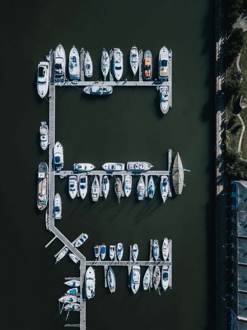 Aerial view of several boats docked at a marina, forming an E-shaped arrangement on dark water. - Home Instead