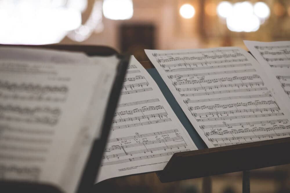 Close-up of musical notes on sheets of paper placed on music stands, with a blurred background. - Home Instead