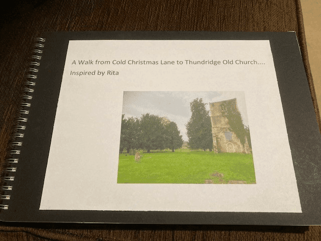 A photo album titled "A Walk from Cold Christmas Lane to Thundridge Old Church... Inspired by Rita" on a table. - Home Instead