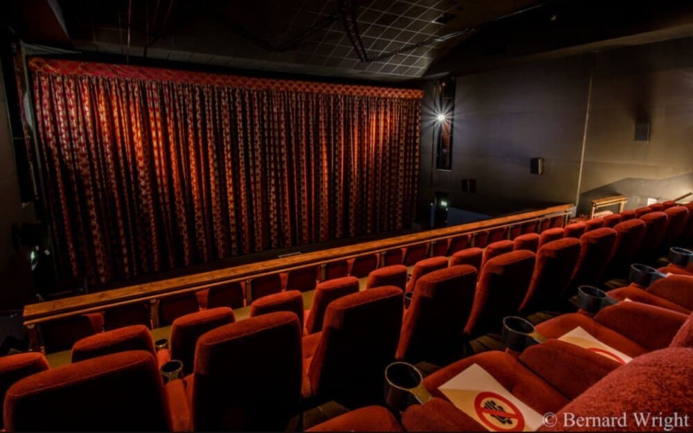Empty theater with red seats and closed red curtains, photo credit to Bernard Wright. - Home Instead