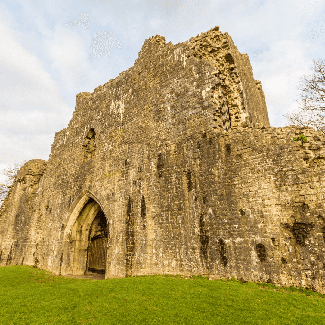Stone ruins of an ancient castle on a grassy lawn under a cloudy sky. - Home Instead