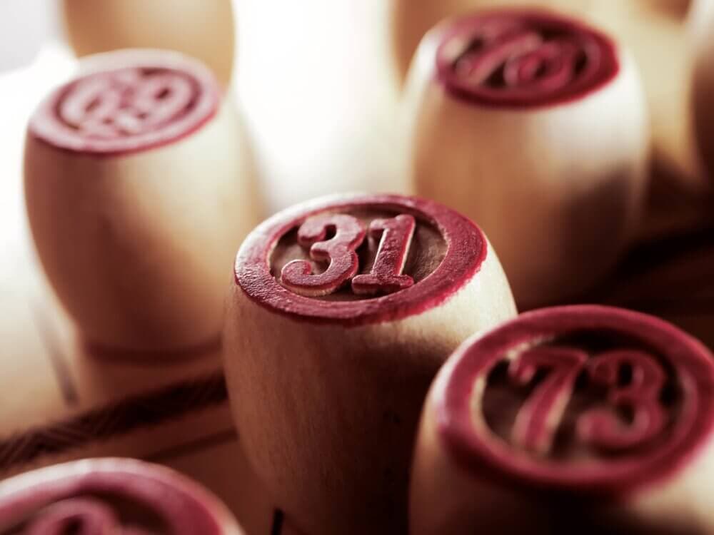 Close-up of wooden bingo barrels with red numbers, focusing on the number 31 in the center. - Home Instead
