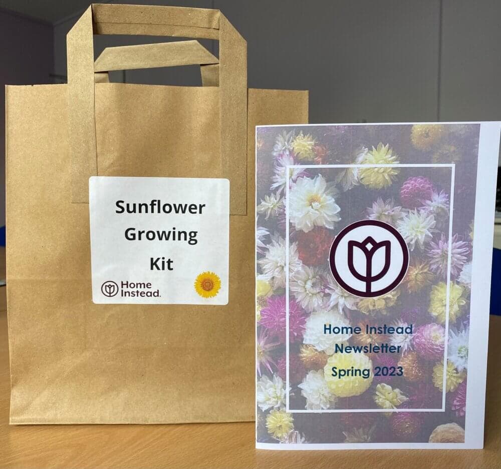 A Sunflower Growing Kit and a "Home Instead Newsletter Spring 2023" booklet on a table. - Home Instead