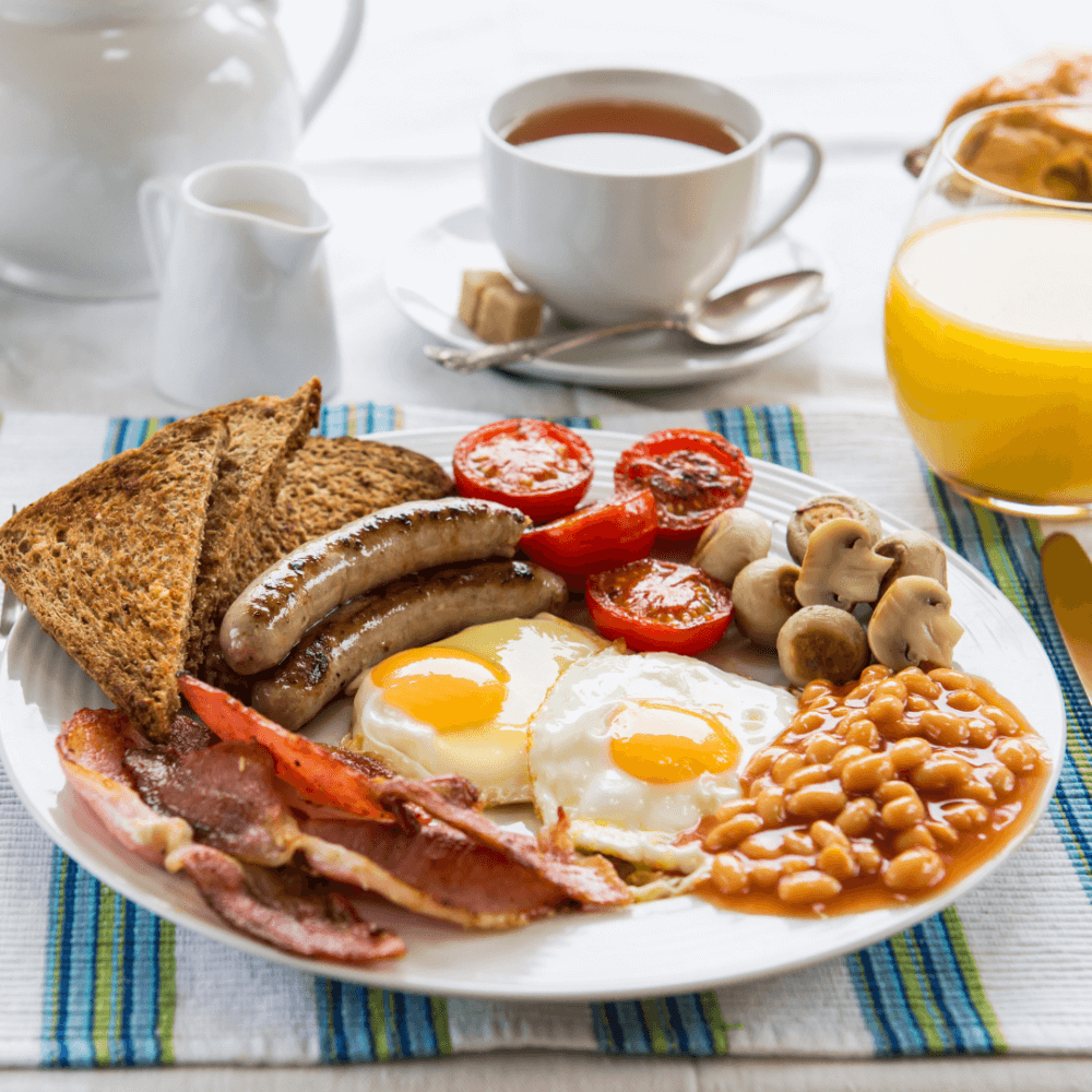A full English breakfast with eggs, bacon, sausages, toast, mushrooms, tomatoes, baked beans, tea, and orange juice. - Home Instead