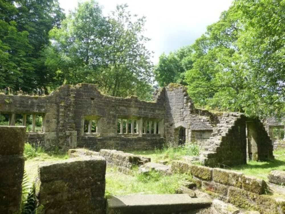 Ruins of an old stone building surrounded by greenery and trees on a sunny day. - Home Instead