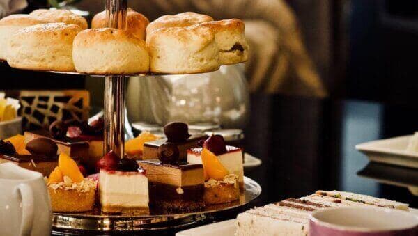 Assorted pastries, scones, and tea sandwiches arranged on a tiered stand for afternoon tea. - Home Instead