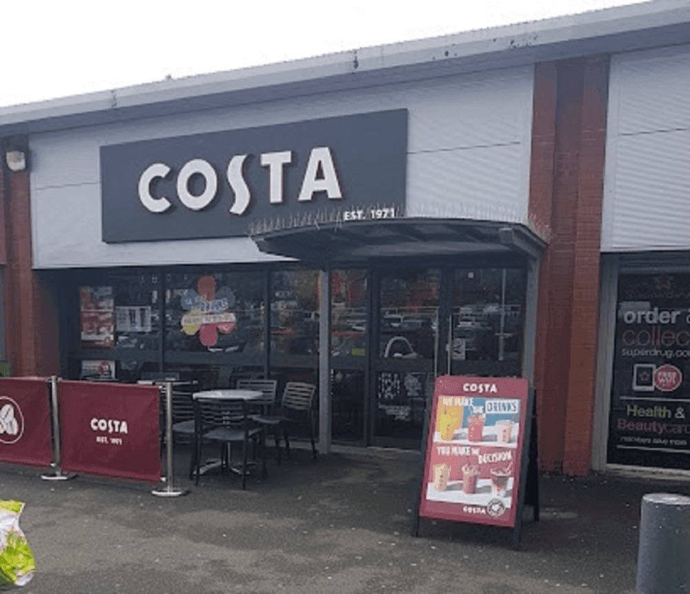Front view of a Costa coffee shop with outdoor seating and promotional signage near the entrance. - Home Instead