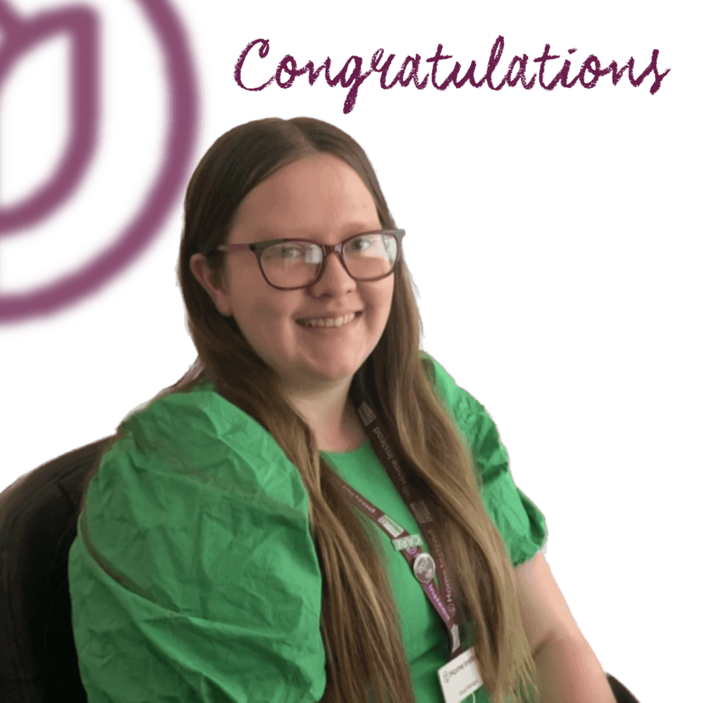 A smiling person with long hair and glasses, wearing a green top and lanyard, with "Congratulations" text above. - Home Instead