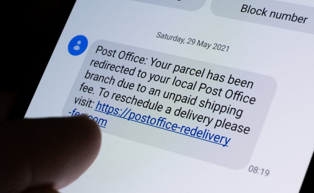 Close-up of a phone screen displaying a phishing text message about an unpaid shipping fee from a fake post office. - Home Instead