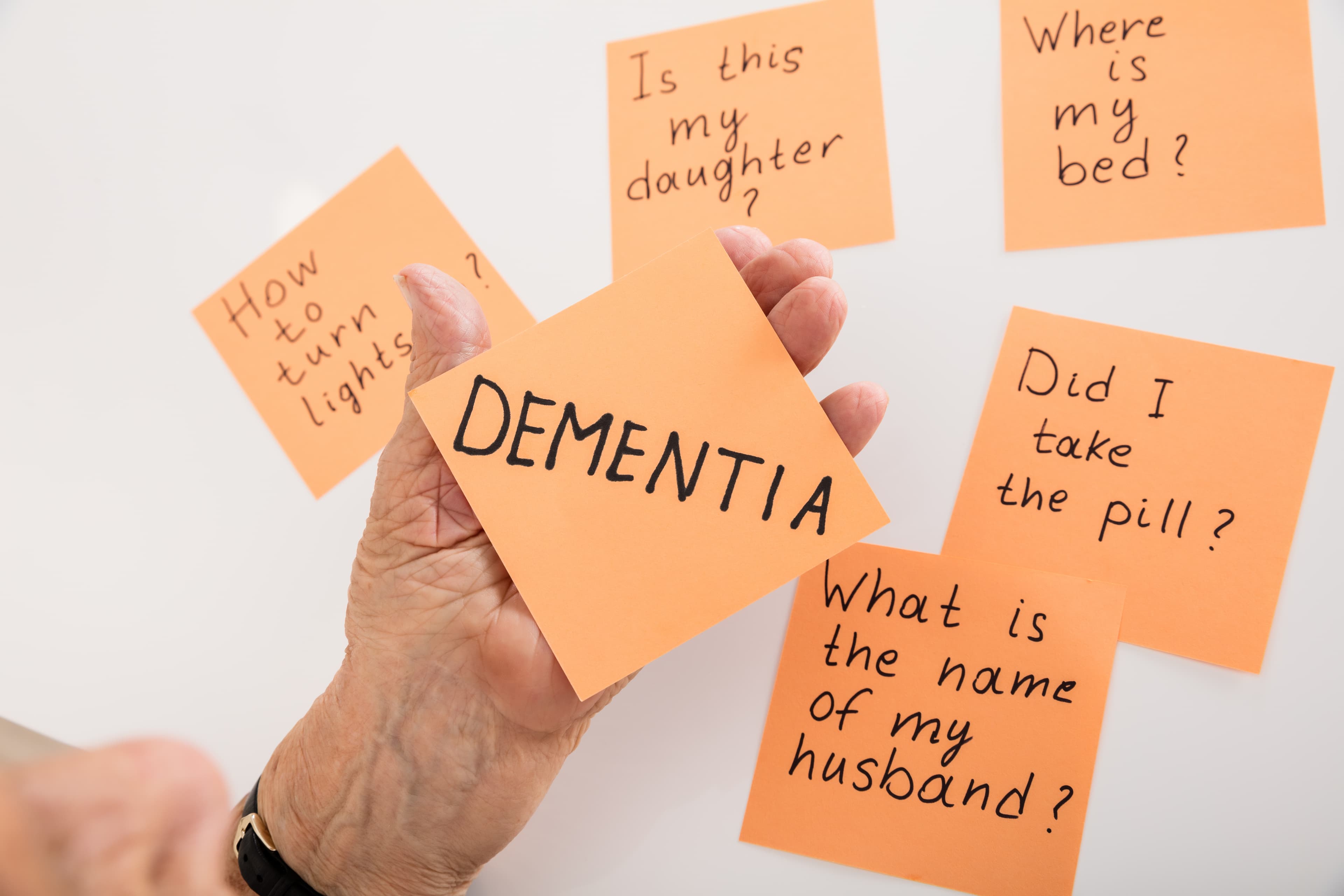 Hand holding numerous sticky notes about dementia - Home Instead