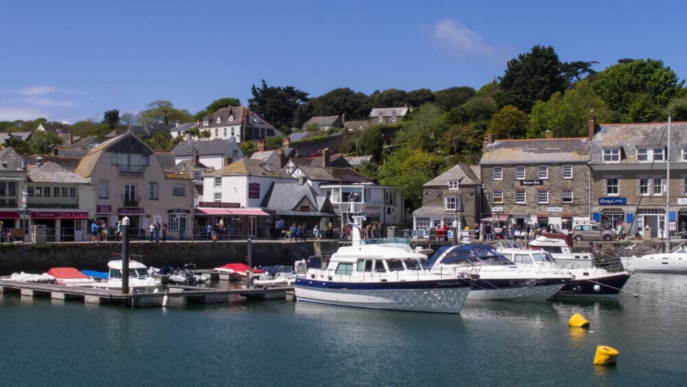 Scenic view of a harbor with boats docked and buildings along the shoreline under a clear blue sky. - Home Instead