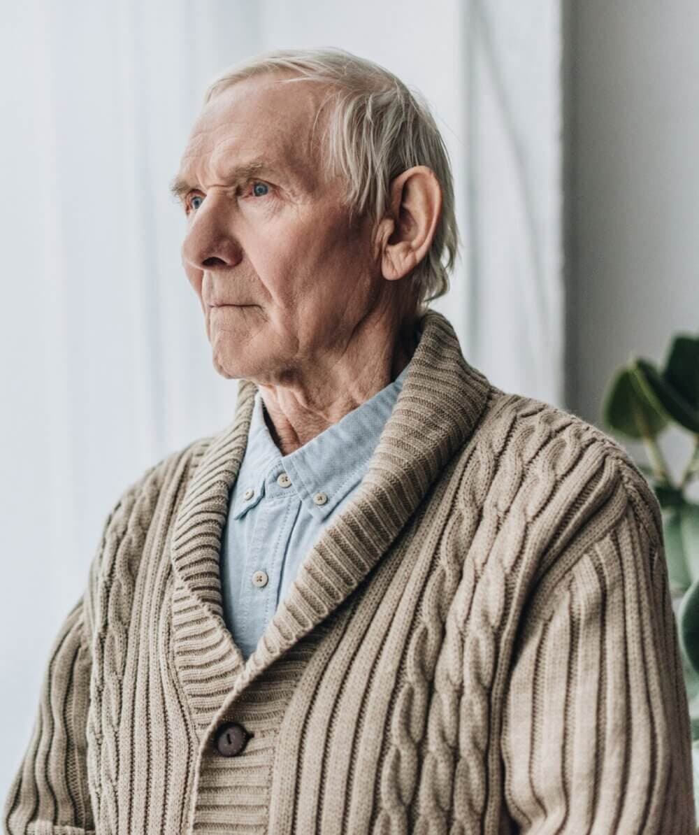 Elderly man with white hair and beard, resting his hands and chin on a cane, looking thoughtful. - Home Instead