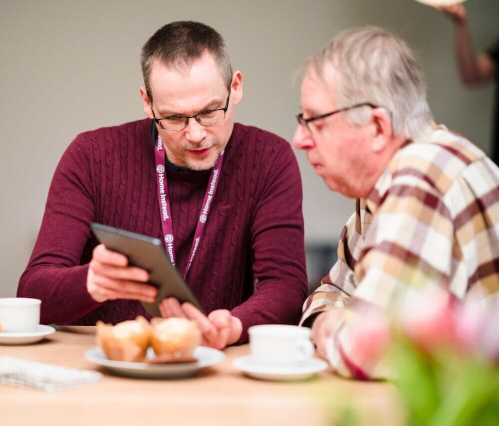 Three women standing by a door, one holding a dog, another arriving with groceries. - Home Instead