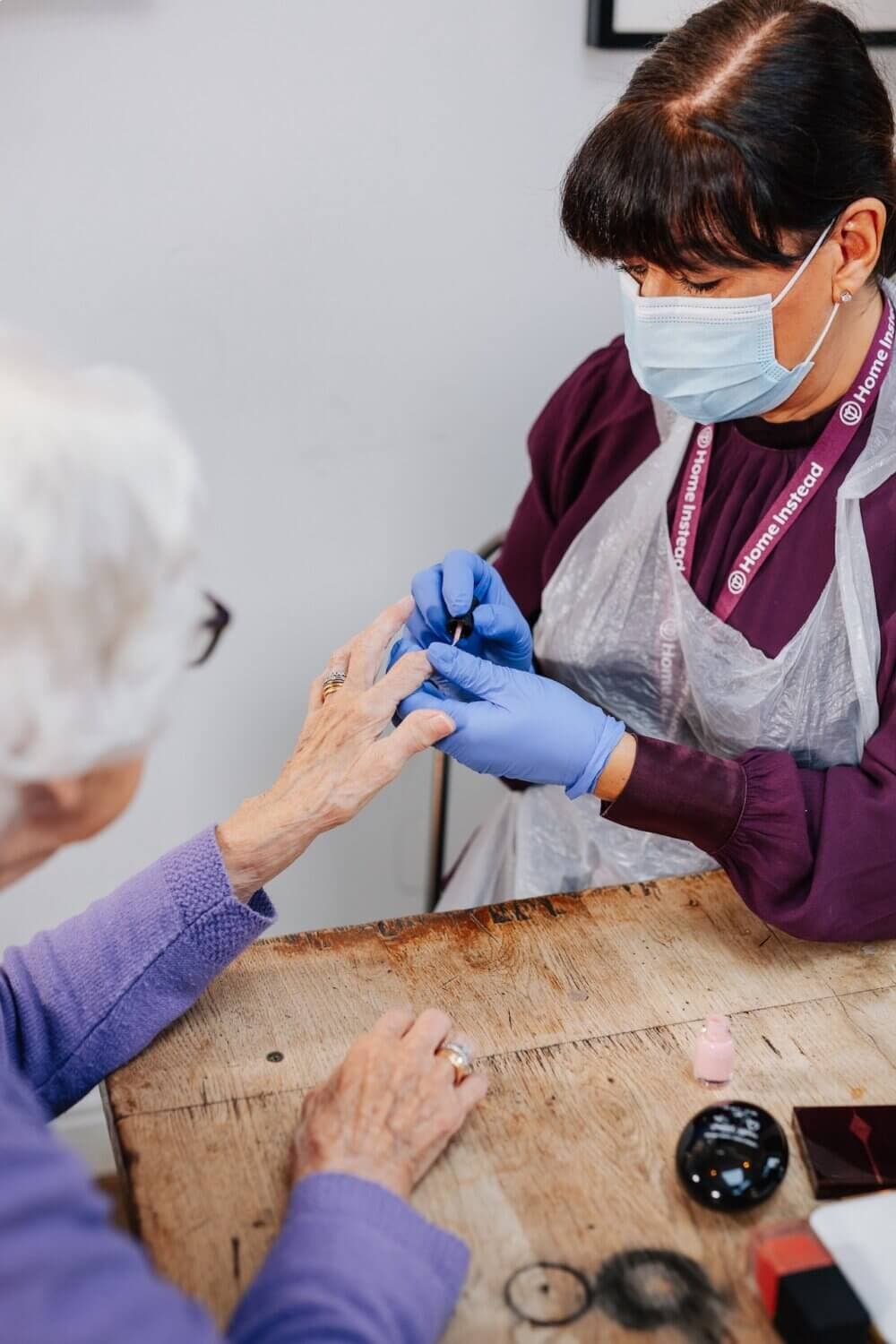 A young woman and an older woman smile while folding clothes together. - Home Instead
