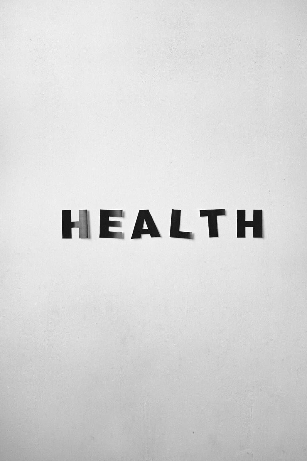 Letters forming the word "HEALTH" are affixed to a plain white wall with black tape. - Home Instead