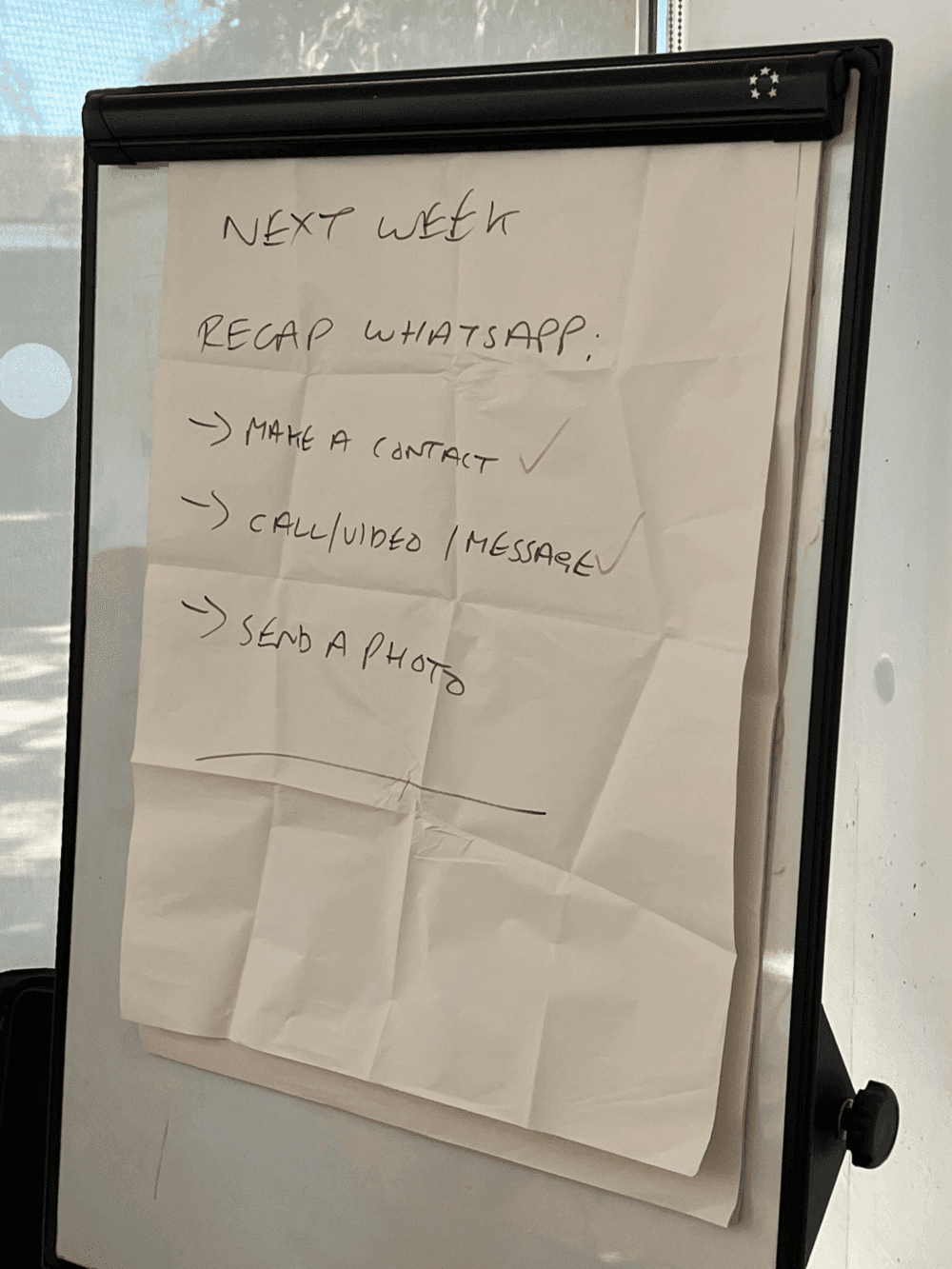 A flip chart with a paper listing "Next week recap WhatsApp": make a contact, call/video/message, send a photo. - Home Instead