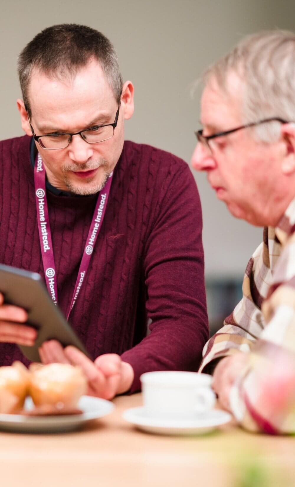 Home Instead Bournemouth & Christchurch Care Professional using tablet with client