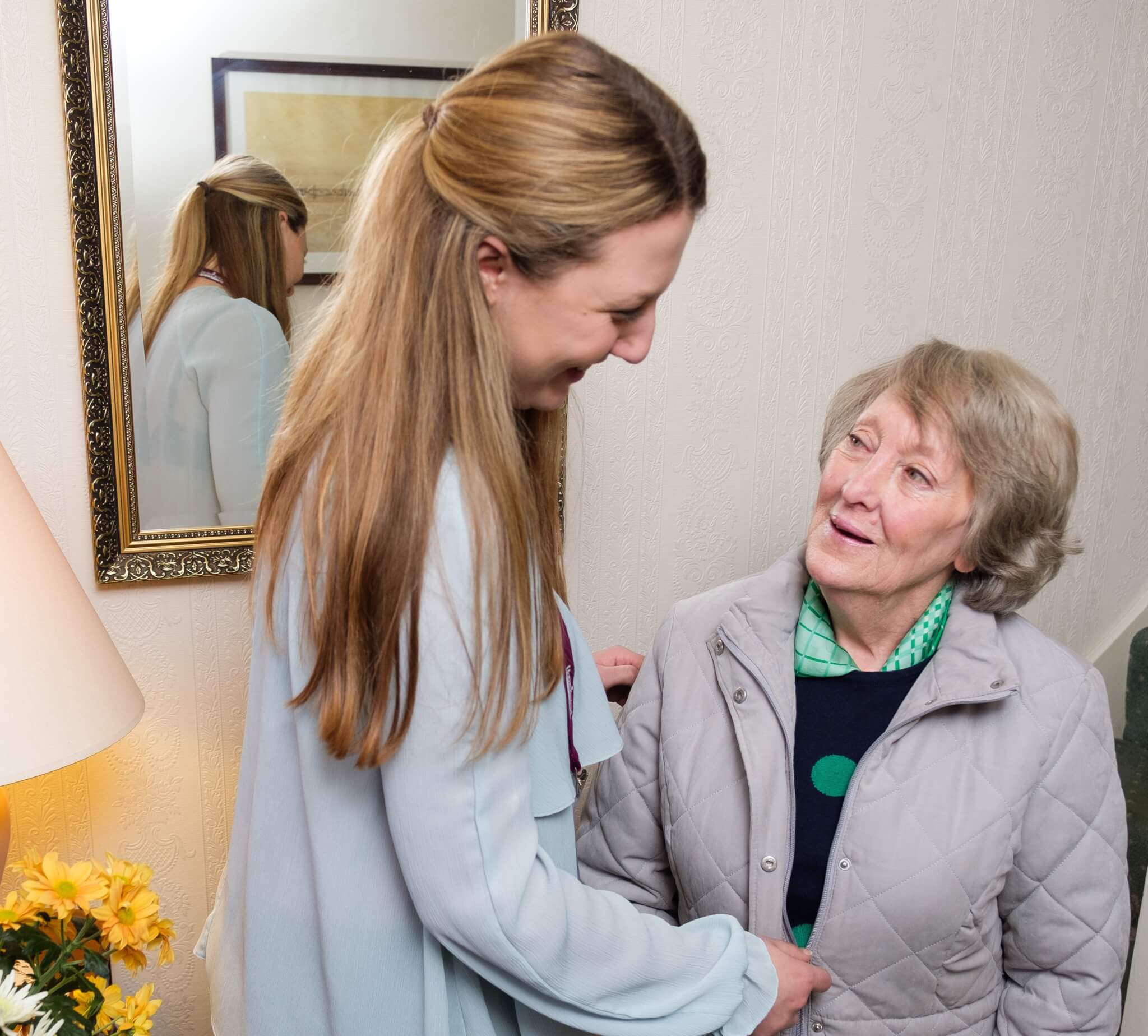 Home Instead carer helping Home Instead client put on her coat