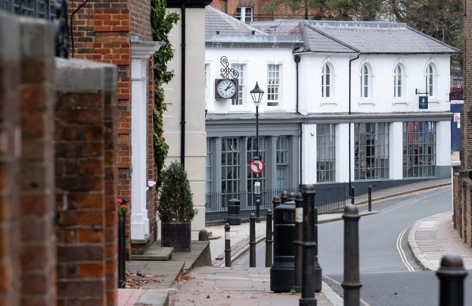 A street with Victorian-style buildings, a clock on the facade, lampposts, and a no entry traffic sign. - Home Instead
