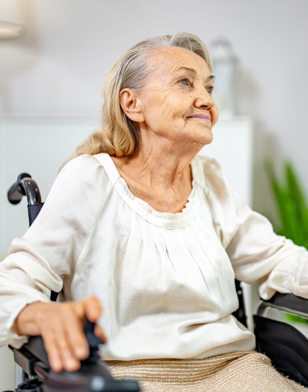 Elderly man with white hair wearing a beige knitted sweater, holding his head with both hands, appearing thoughtful. - Home Instead