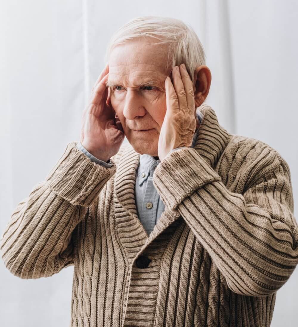 Older man looking stressed while sitting at a table with a younger man beside him, both looking at a laptop screen. - Home Instead