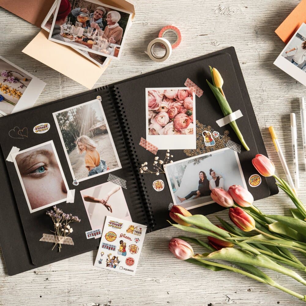 A scrapbook with photos, tulips, and craft supplies on a wooden table. - Home Instead