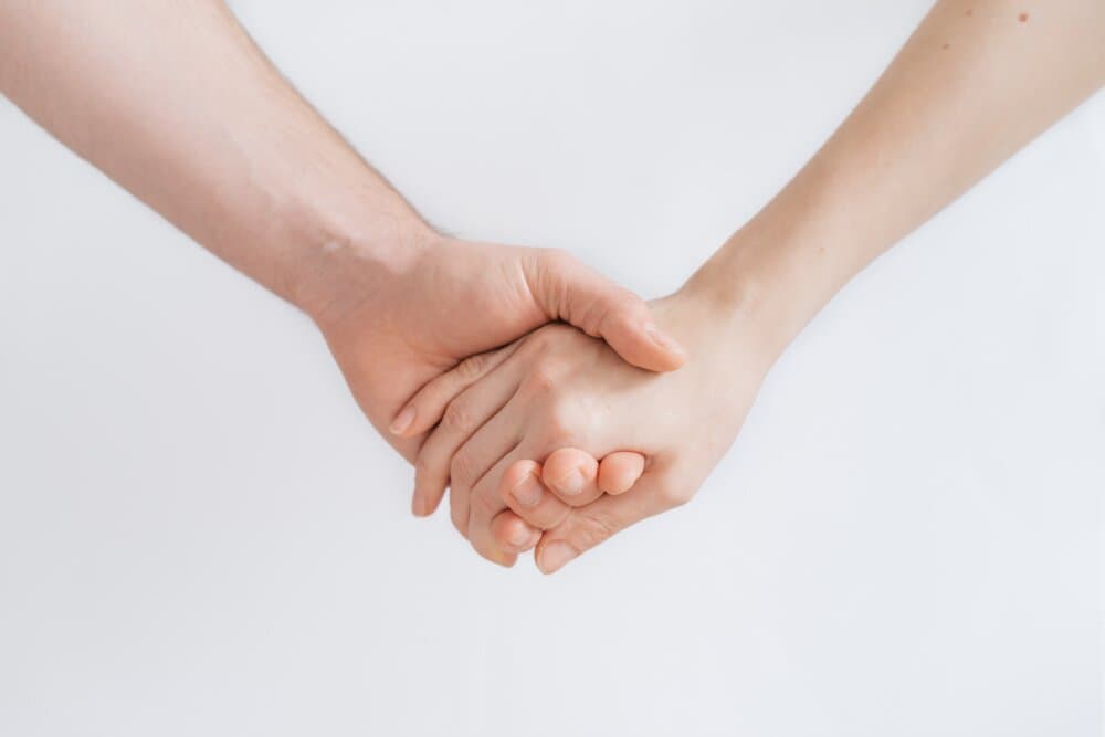 Two people holding hands against a plain white background. - Home Instead
