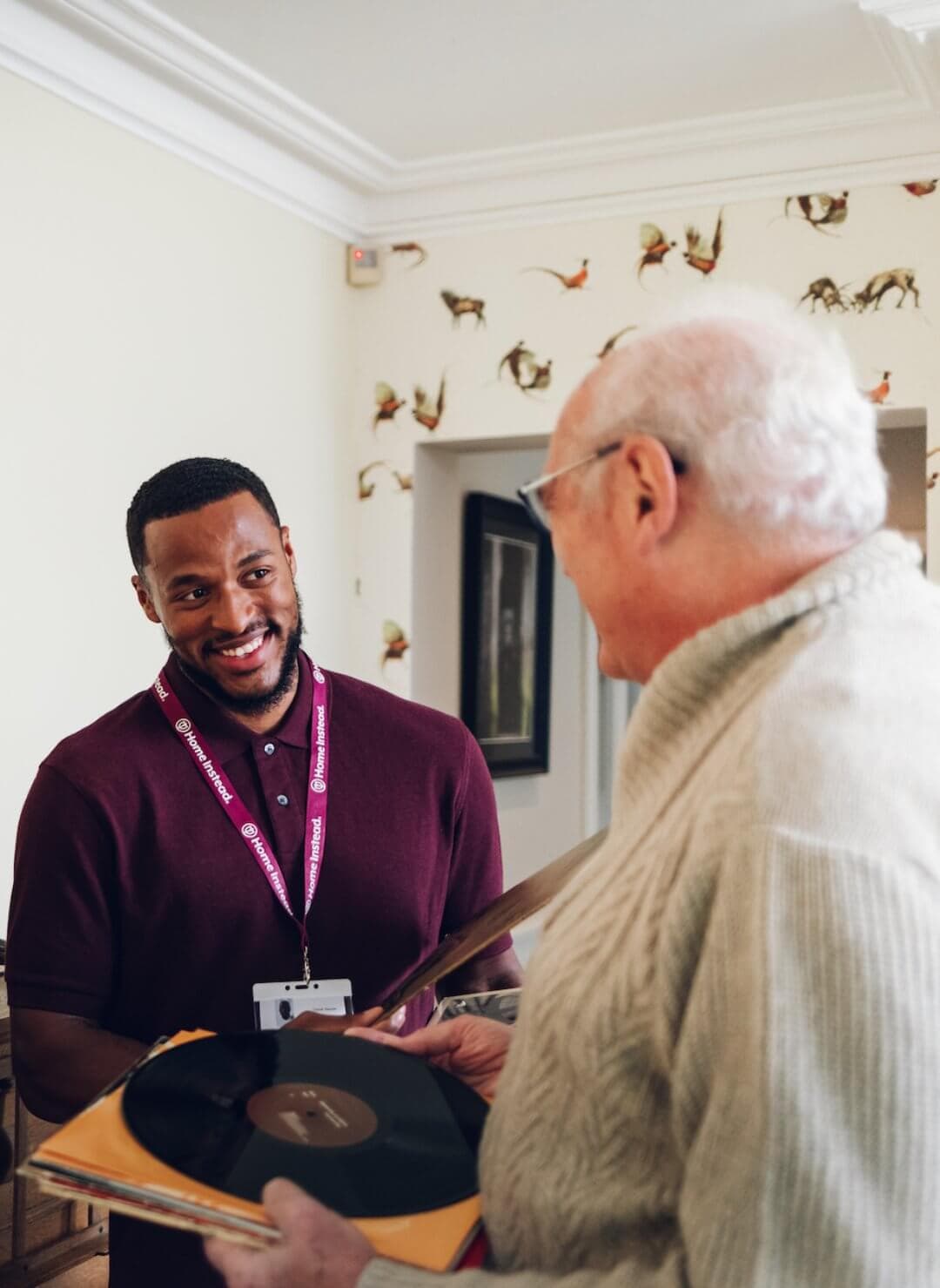 Dementia Care client with vinyl record and Home Instead Poole Care Professional