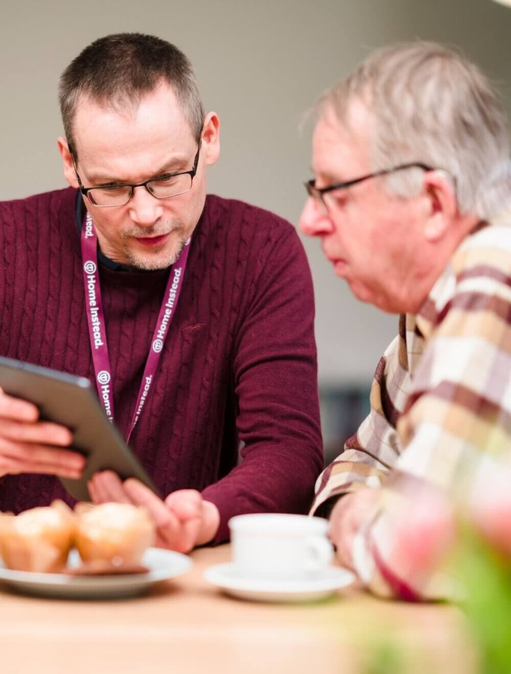An elderly woman and a caregiver sharing a joyful moment while looking at a book together. - Home Instead