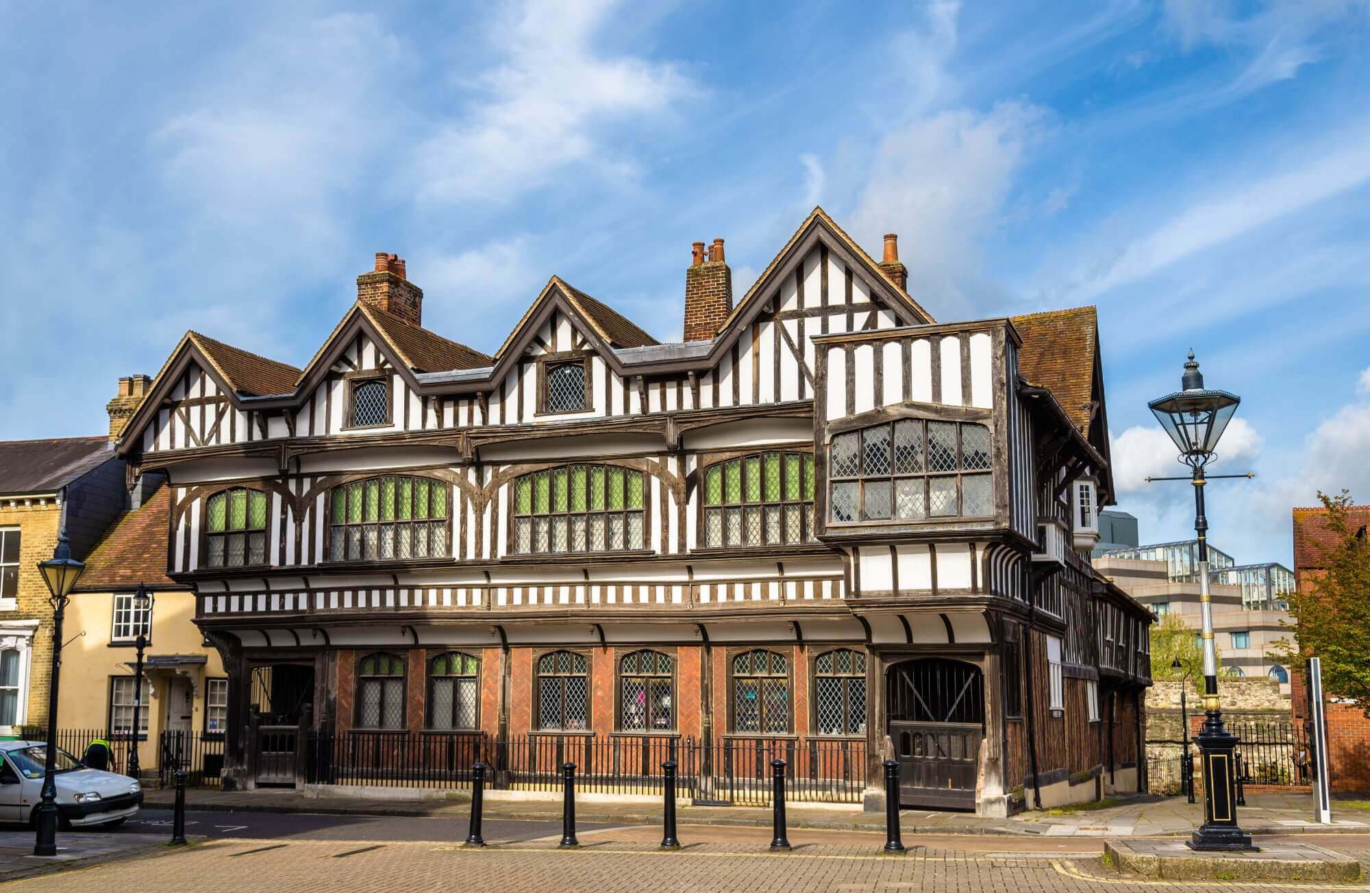 A historic half-timbered building with gabled roofs, black-and-white exterior, and large windows against a blue sky. - Home Instead Southampton