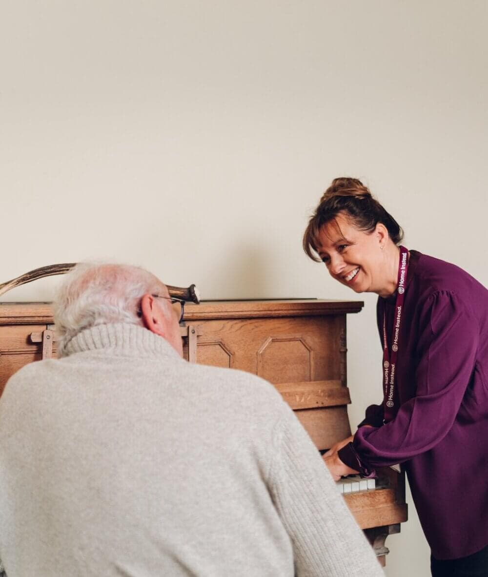 Elderly male client playing the piano with Home Instead Poole Care Professional