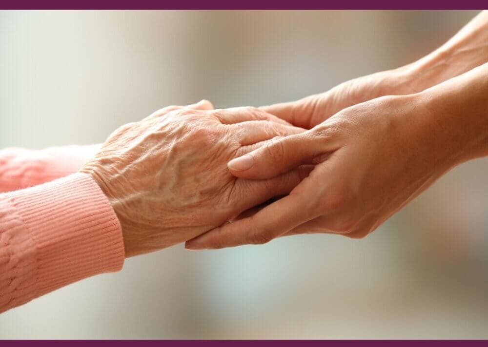 A younger hand gently holds and supports an elderly hand, signifying care and support. - Home Instead