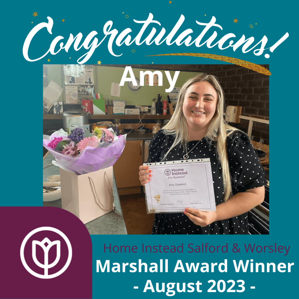A woman named Amy, smiling and holding a certificate next to a bouquet of flowers. Text: "Marshall Award Winner - August 2023". - Home Instead