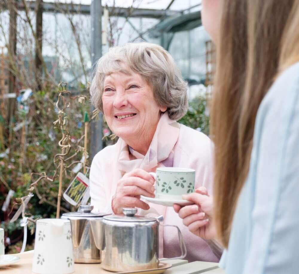 Home Instead client and her Home Instead carer having tea at a garden centre